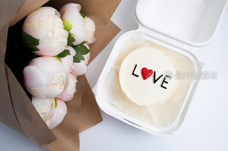便当蛋糕，上面写着"爱与心"还有一束花。一个可爱的甜点礼物，适合任何场合给你爱的人。贺卡。爱情与糖果概念